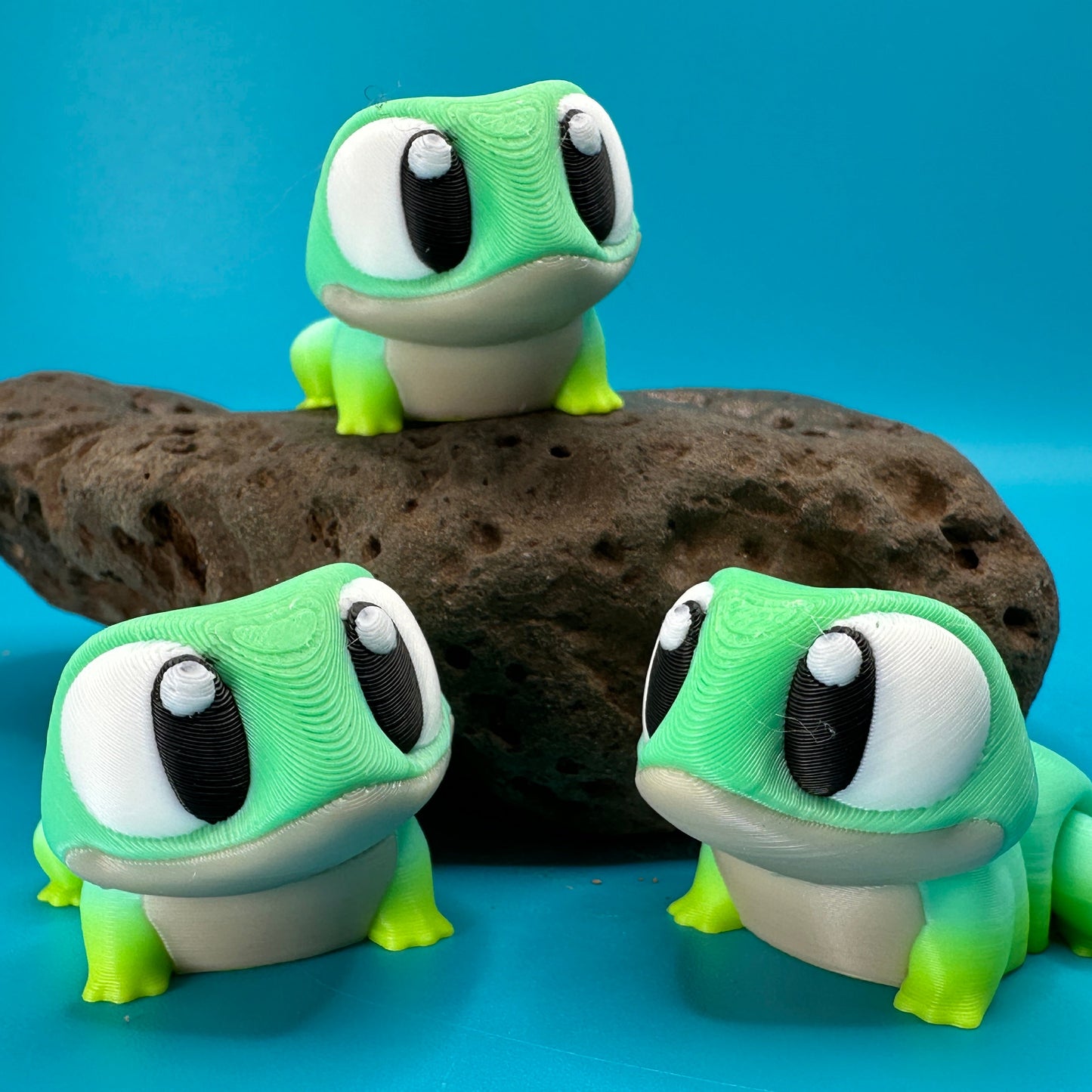 Three green frog-like figurines on a blue background