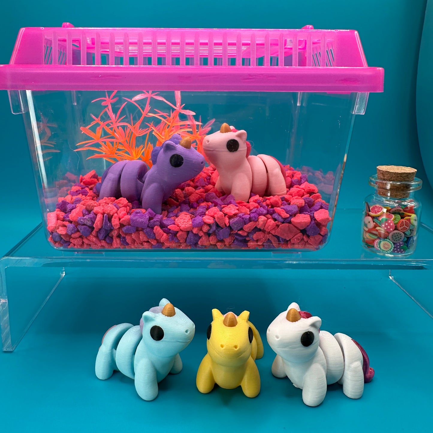 Small aquarium with colorful fish and a pink ladder, next to small toy animals on a blue background